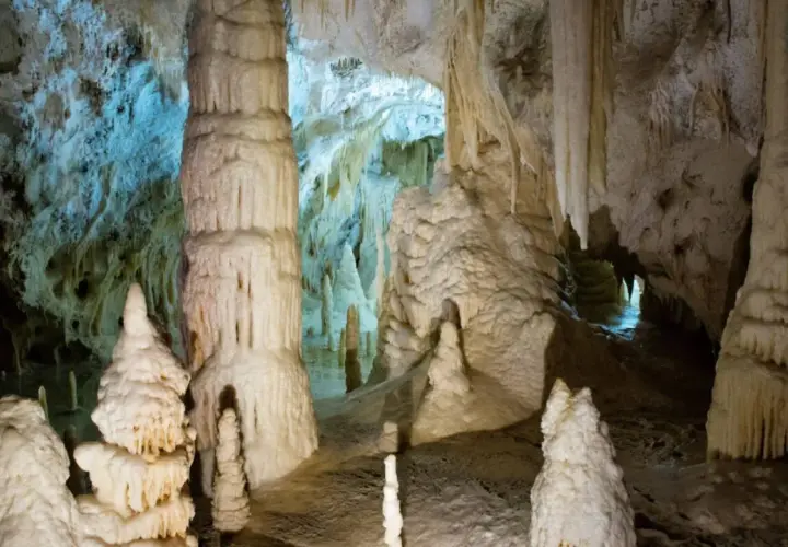 Stalattiti e stalagmiti imponenti nelle Grotte di Genga, Marche, creano un paesaggio sotterraneo surreale.