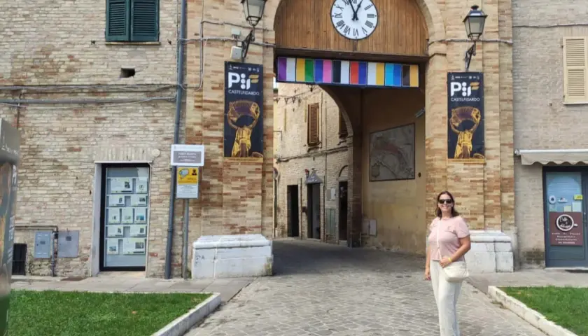 Una donna sorride sotto l'arco di Porta San Martino a Castelfidardo, un luogo ricco di storia e musica da scoprire.