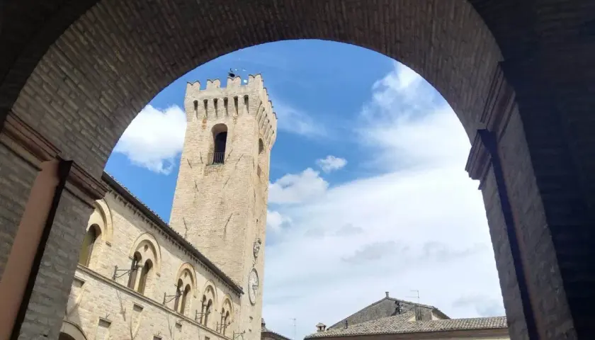 Arco in mattoni incornicia la torre civica e il palazzo comunale di Montelupone, un luogo da scoprire.