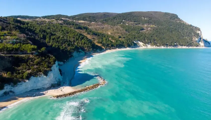 Vista aerea della spiaggia di Numana Alta, con le sue scogliere bianche, la pineta e il mare cristallino.