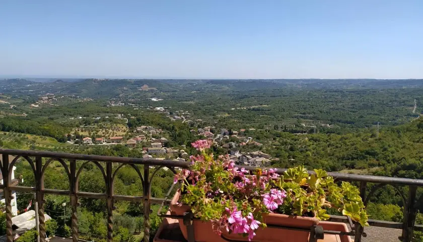 Vista panoramica su un borgo tra colline verdi. Un balcone fiorito offre un'ottima prospettiva su cosa vedere a Pretoro.