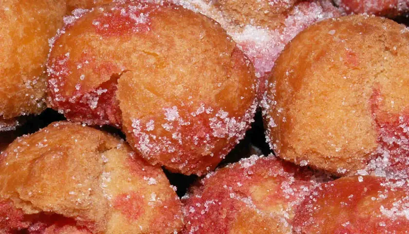 Scroccafusi di Macerata, dolcetti dorati e rosati, cosparsi di zucchero cristallino, pronti per essere gustati.