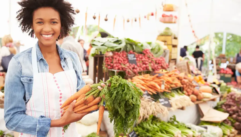 Donna sorridente al mercato con carote fresche, un vero km zero menù.