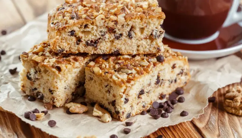 Fette di ciambellone marchigiano ricetta originale, con gocce di cioccolato e noci, accanto a una tazza di caffè.
