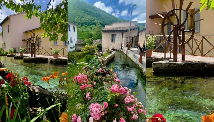 A picturesque village with a clear stream flowing through it, lined with flowers and old buildings.