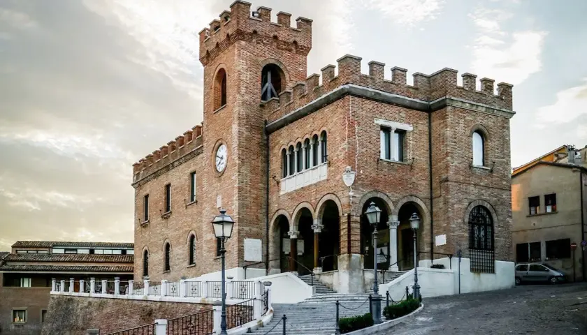 Edificio storico in mattoni a Mondolfo, cosa vedere: torre con orologio, archi e scalinata.