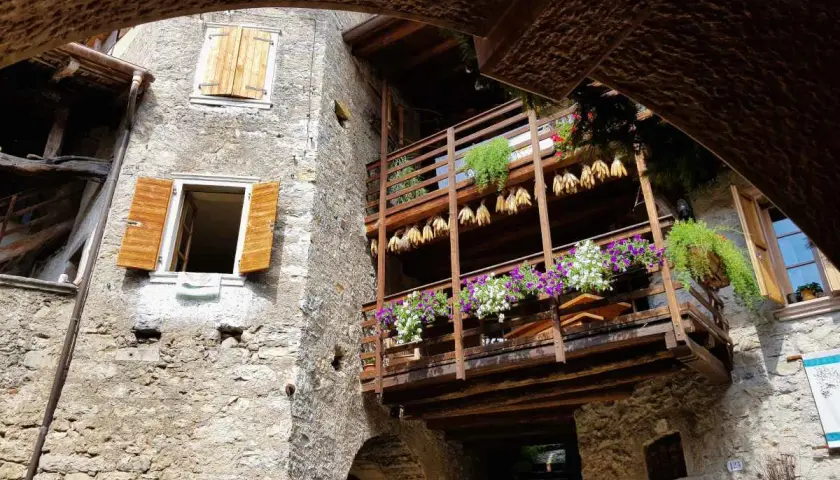 Un vicolo suggestivo nel canale di Tenno, con balconi fioriti e scorci antichi da scoprire.