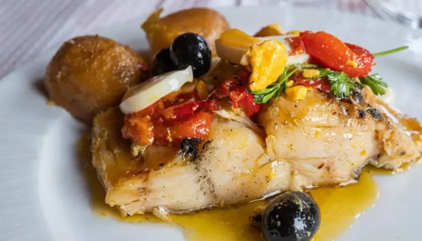 Stoccafisso all'Anconetana con patate, olive nere, pomodorini e uovo sodo. Un piatto ricco e saporito.