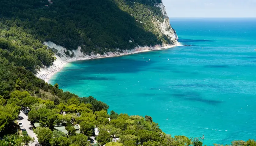 Spiaggia affollata e mare turchese, un campeggio immerso nel verde. Perfetto per scoprire le località balneari Marche economiche.