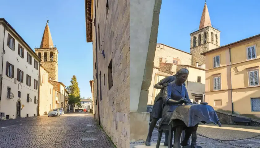 Sansepolcro cosa vedere: una piazza con una scultura di donne al lavoro, campanili medievali e palazzi storici sotto un cielo azzurro.