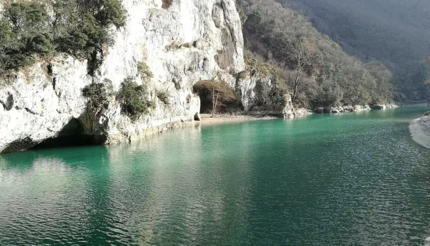 Acqualagna cosa vedere: un lago smeraldo incastonato tra imponenti pareti rocciose con grotte naturali.