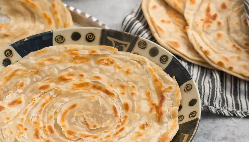 Crescia marchigiana dorata e sfogliata, servita su un piatto decorato. Un sapore autentico delle Marche.