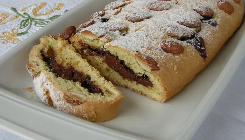 Ciambellone marchigiano con ripieno goloso di Nutella, decorato con mandorle e zucchero a velo.