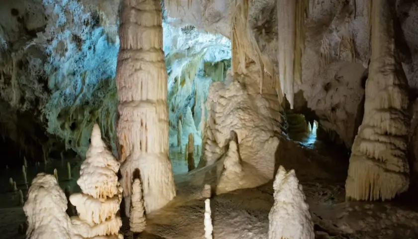Stalattiti e stalagmiti imponenti nelle Grotte di Genga, Marche, creano un paesaggio sotterraneo surreale.