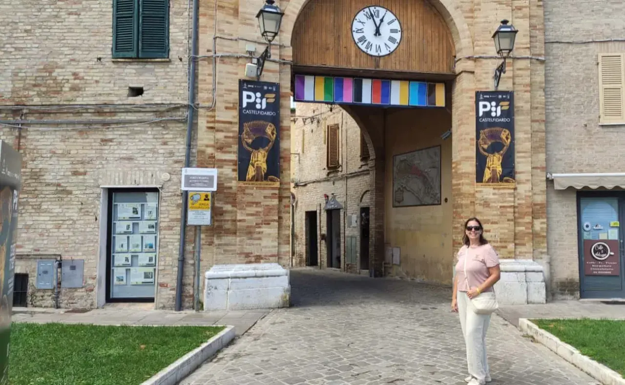 Una donna sorride sotto l'arco di Porta San Martino a Castelfidardo, un luogo ricco di storia e musica da scoprire.