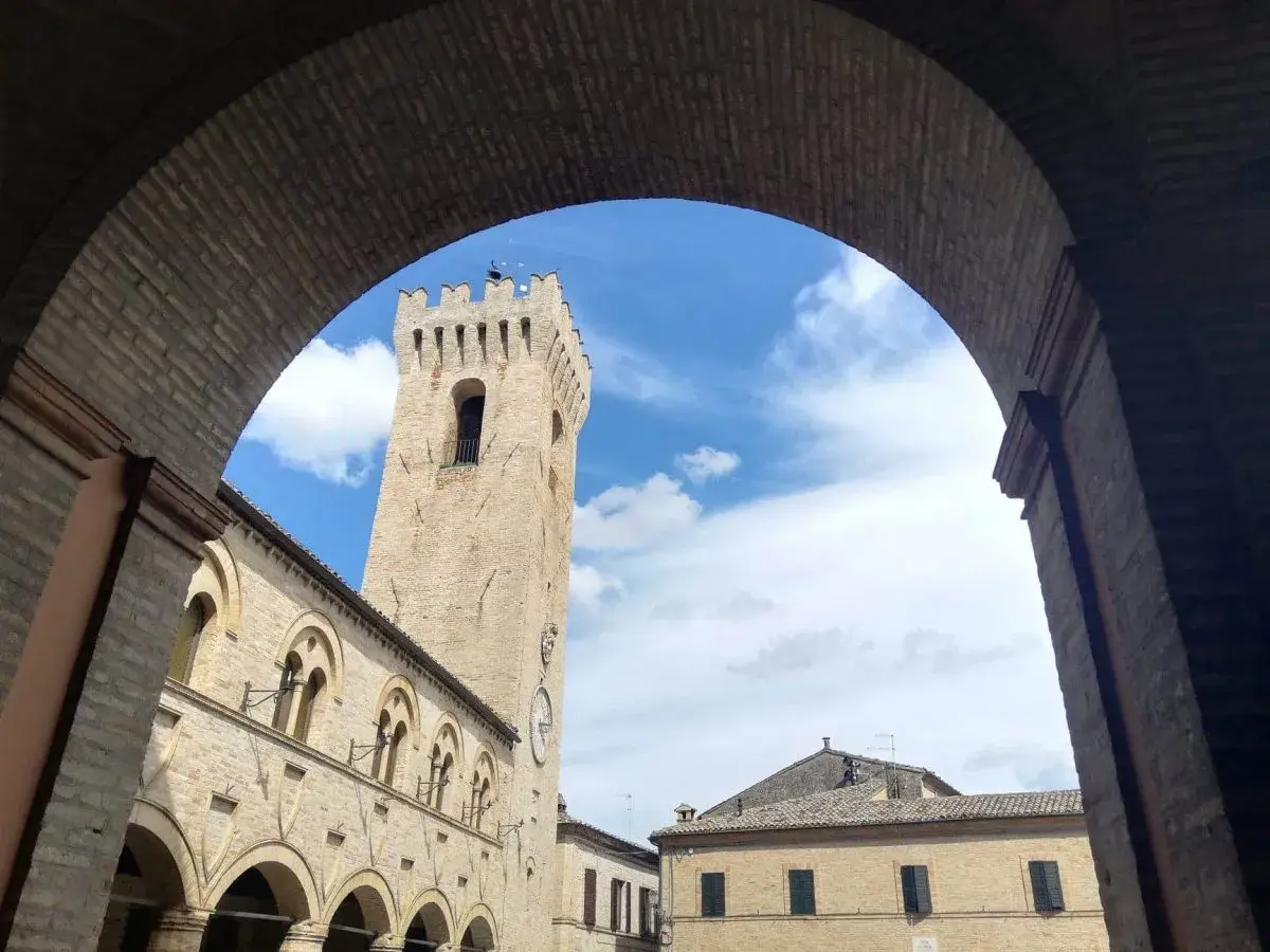 Arco in mattoni incornicia la torre civica e il palazzo comunale di Montelupone, un luogo da scoprire.