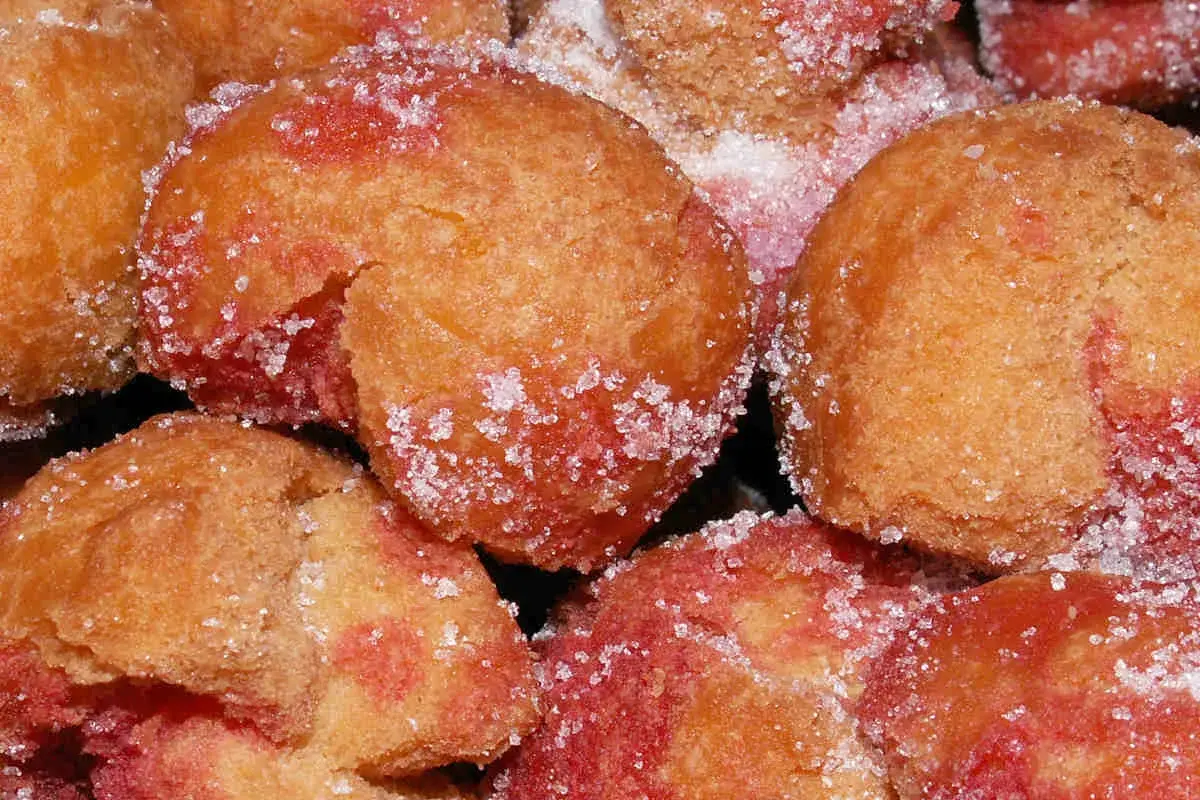 Scroccafusi di Macerata, dolcetti dorati e rosati, cosparsi di zucchero cristallino, pronti per essere gustati.