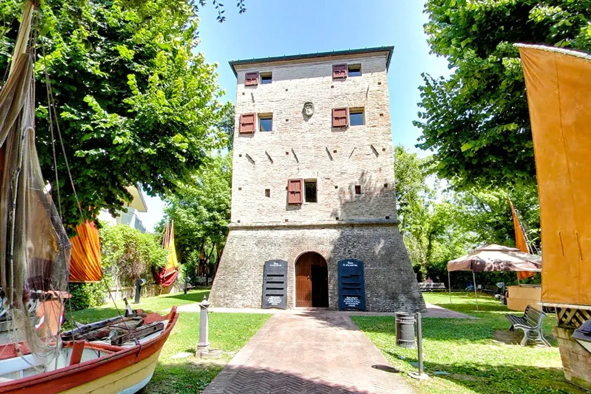 Torre dell'orologio nel centro storico di Igea Marina, con barche e bandiere colorate.