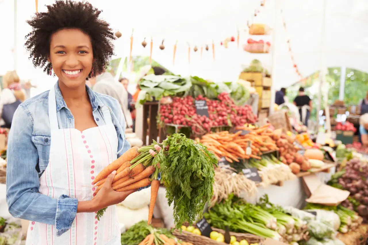 Donna sorridente al mercato con carote fresche, un vero km zero menù.