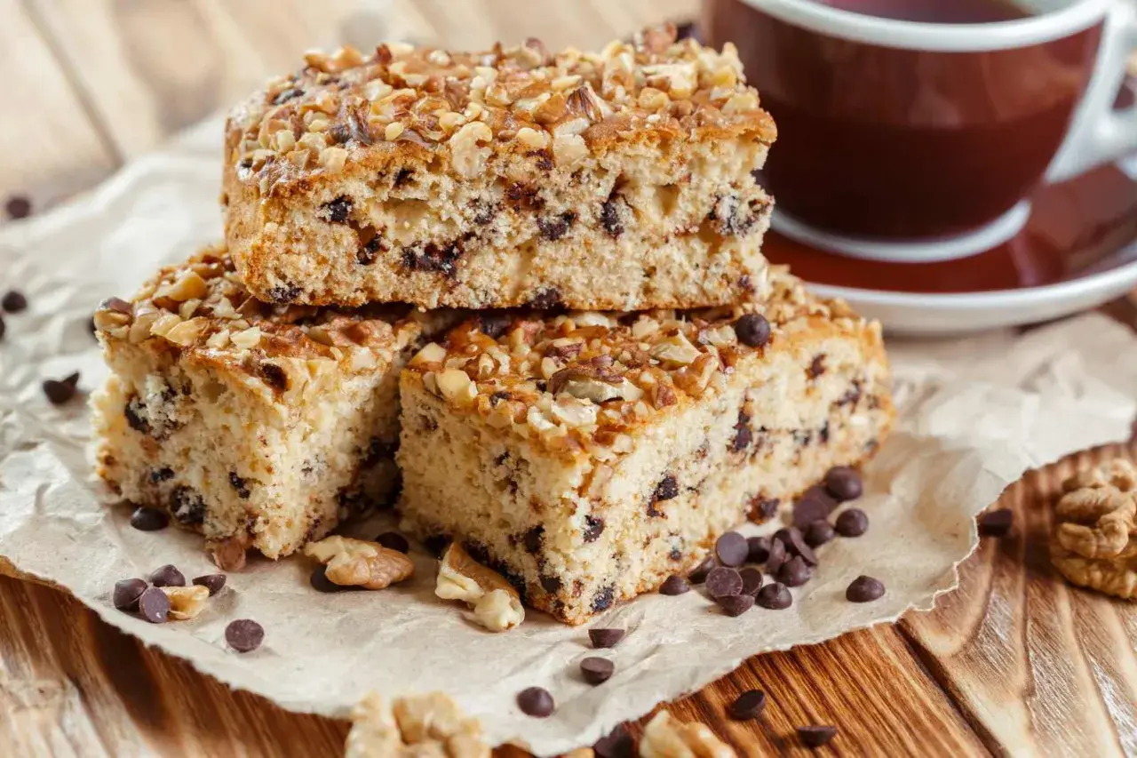 Fette di ciambellone marchigiano ricetta originale, con gocce di cioccolato e noci, accanto a una tazza di caffè.