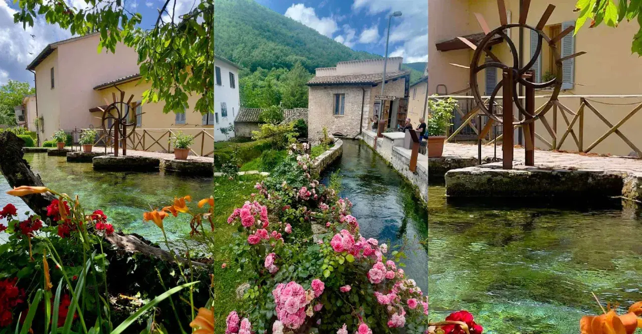 A picturesque village with a clear stream flowing through it, lined with flowers and old buildings.