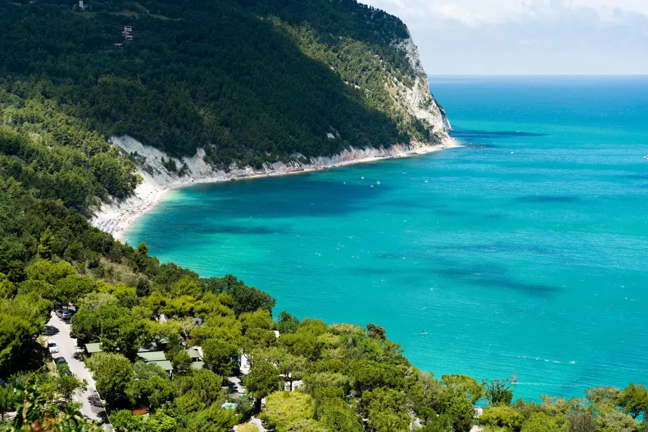 Spiaggia affollata e mare turchese, un campeggio immerso nel verde. Perfetto per scoprire le località balneari Marche economiche.