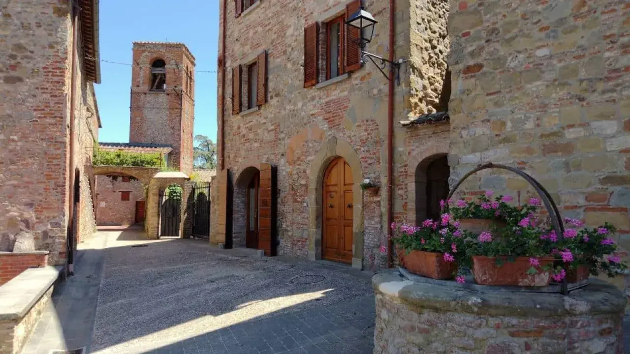 Un vicolo in pietra con un pozzo fiorito e un campanile sullo sfondo. Citerna cosa vedere: un borgo medievale incantevole.