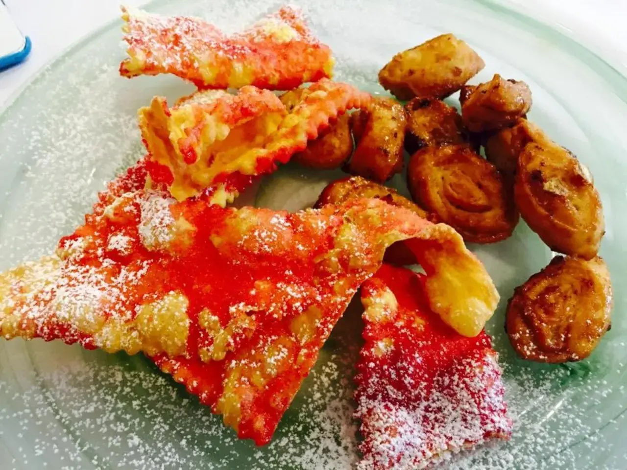 Cresciole marchigiane di Benedetta, dolci fritti cosparsi di zucchero a velo, con un tocco di rosso vivace.