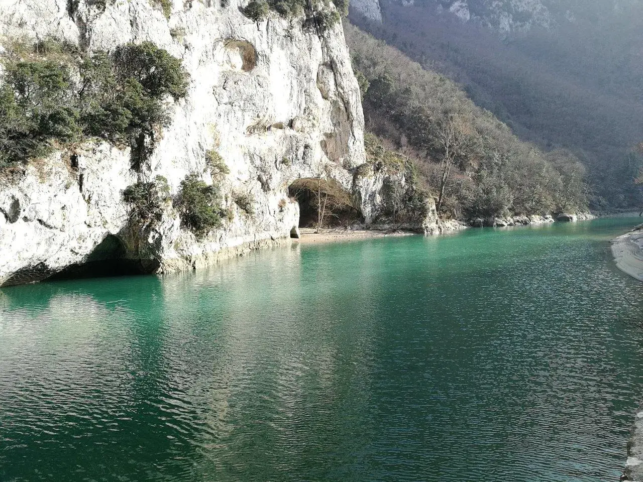 Acqualagna cosa vedere: un lago smeraldo incastonato tra imponenti pareti rocciose con grotte naturali.