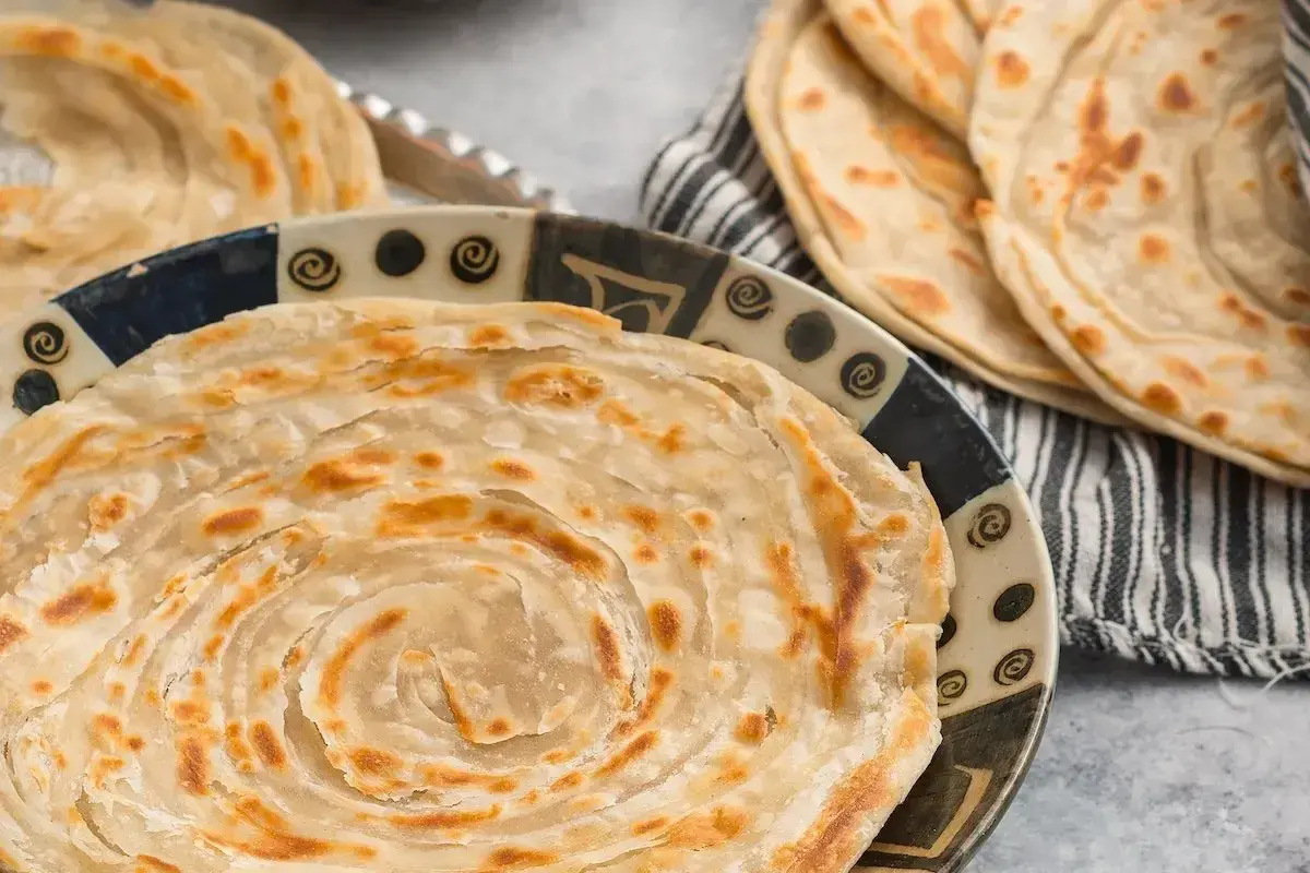 Crescia marchigiana dorata e sfogliata, servita su un piatto decorato. Un sapore autentico delle Marche.