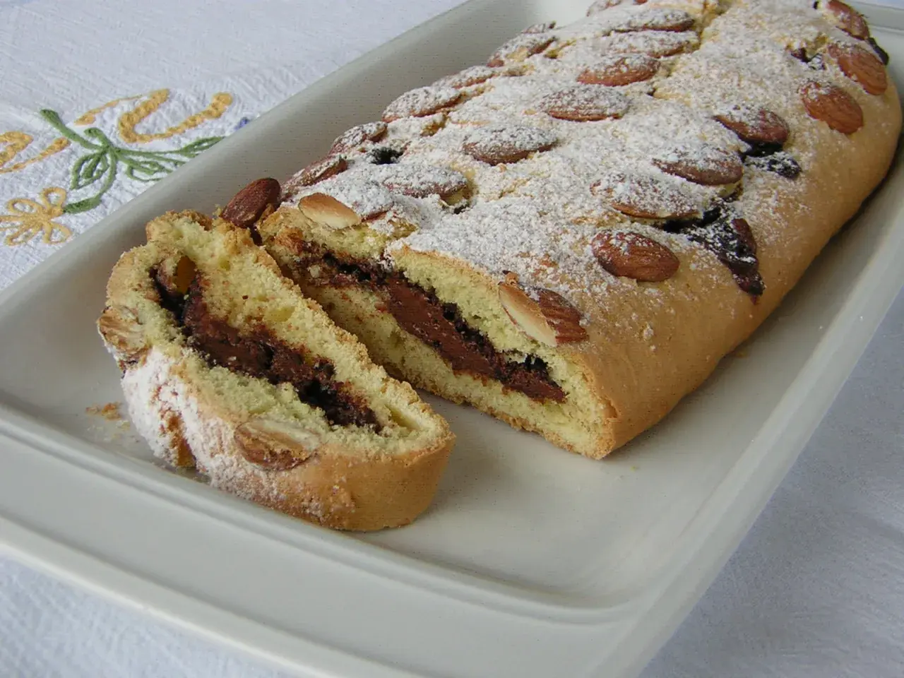 Ciambellone marchigiano con ripieno goloso di Nutella, decorato con mandorle e zucchero a velo.