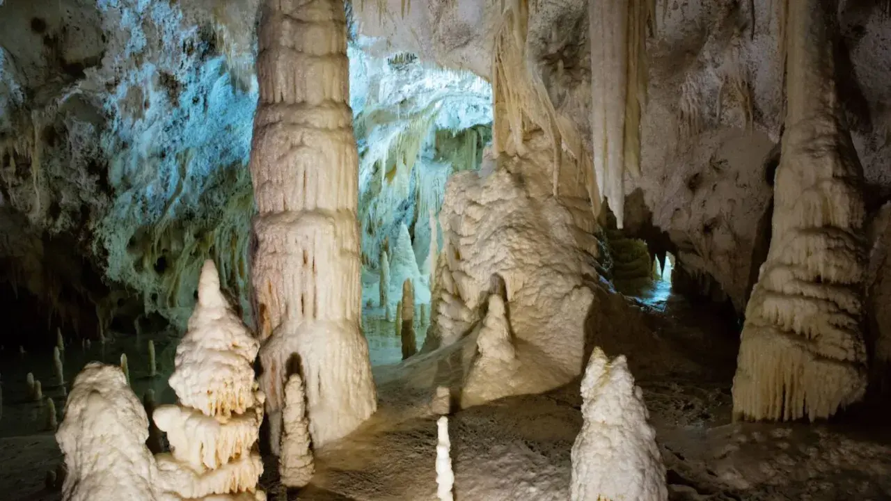 Stalattiti e stalagmiti imponenti nelle Grotte di Genga, Marche, creano un paesaggio sotterraneo surreale.