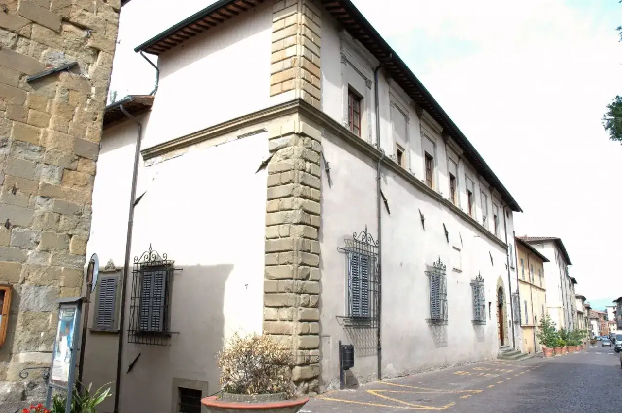 Edifici storici a Sansepolcro, cosa vedere: un angolo di palazzo con finestre ornate e un muro in pietra grezza.