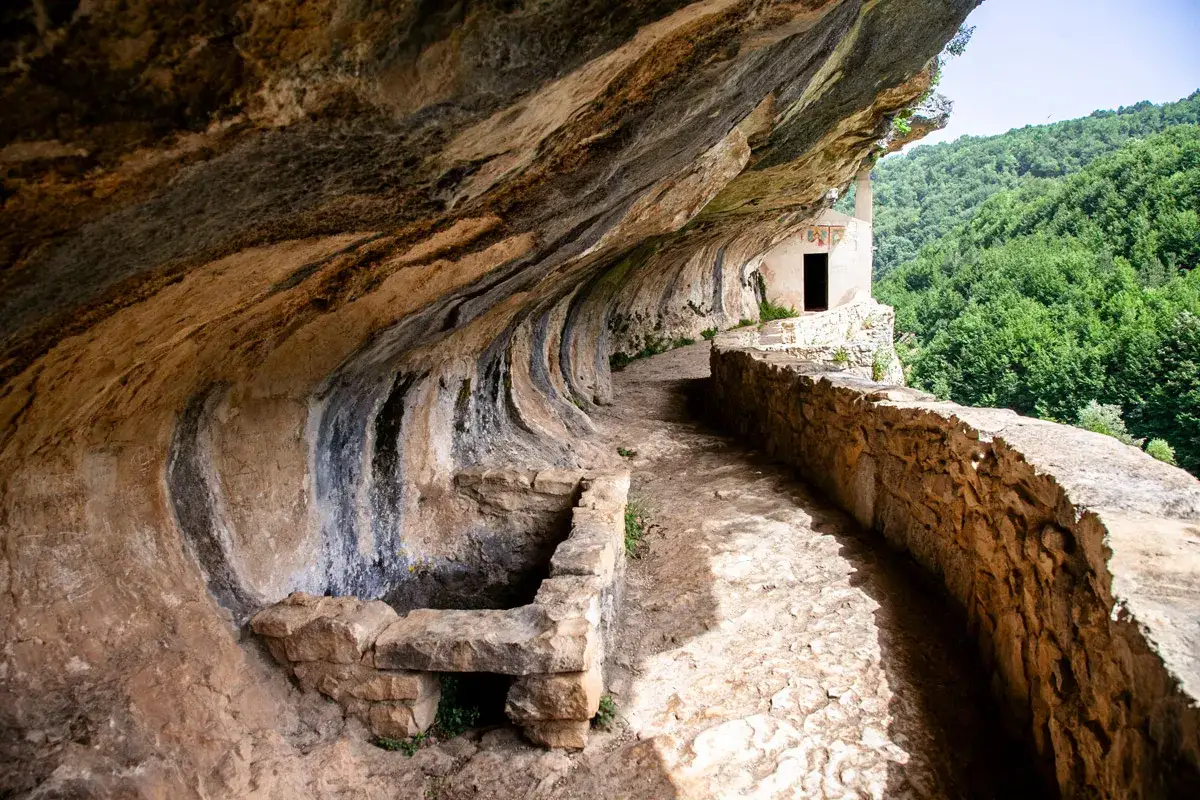 Sentiero roccioso verso l'eremo di San Bartolomeo, incastonato nella roccia con vista su un bosco rigoglioso. Come arrivare?