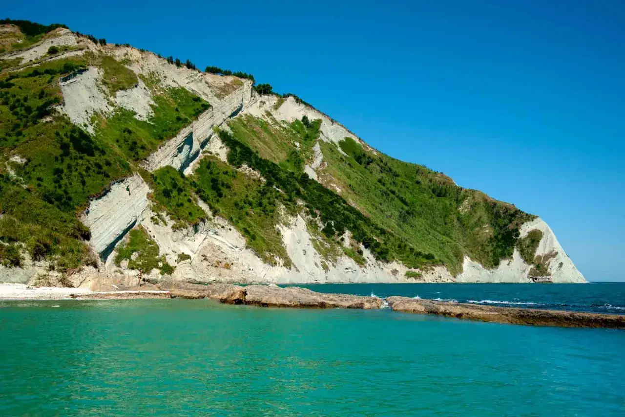 Scogliere verdi e bianche si tuffano nel mare turchese della spiaggia del Trave.
