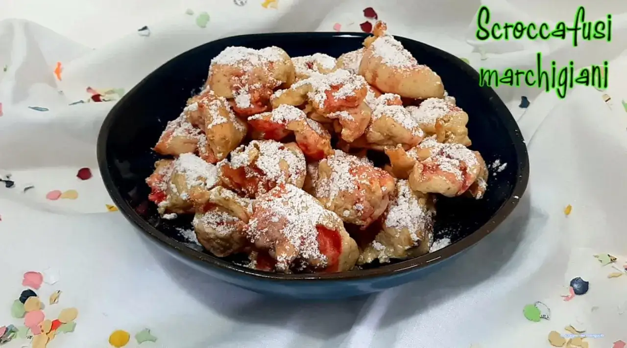Scroccafusi marchigiani, dolcetti fritti cosparsi di zucchero a velo, pronti per essere gustati.