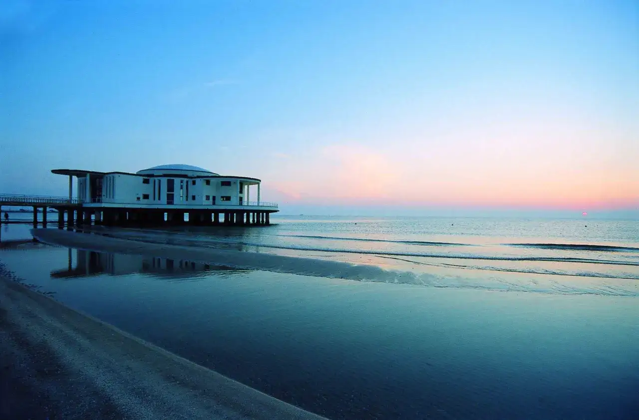 Edificio moderno sul mare a Senigallia, con riflessi sull'acqua e cielo al tramonto.