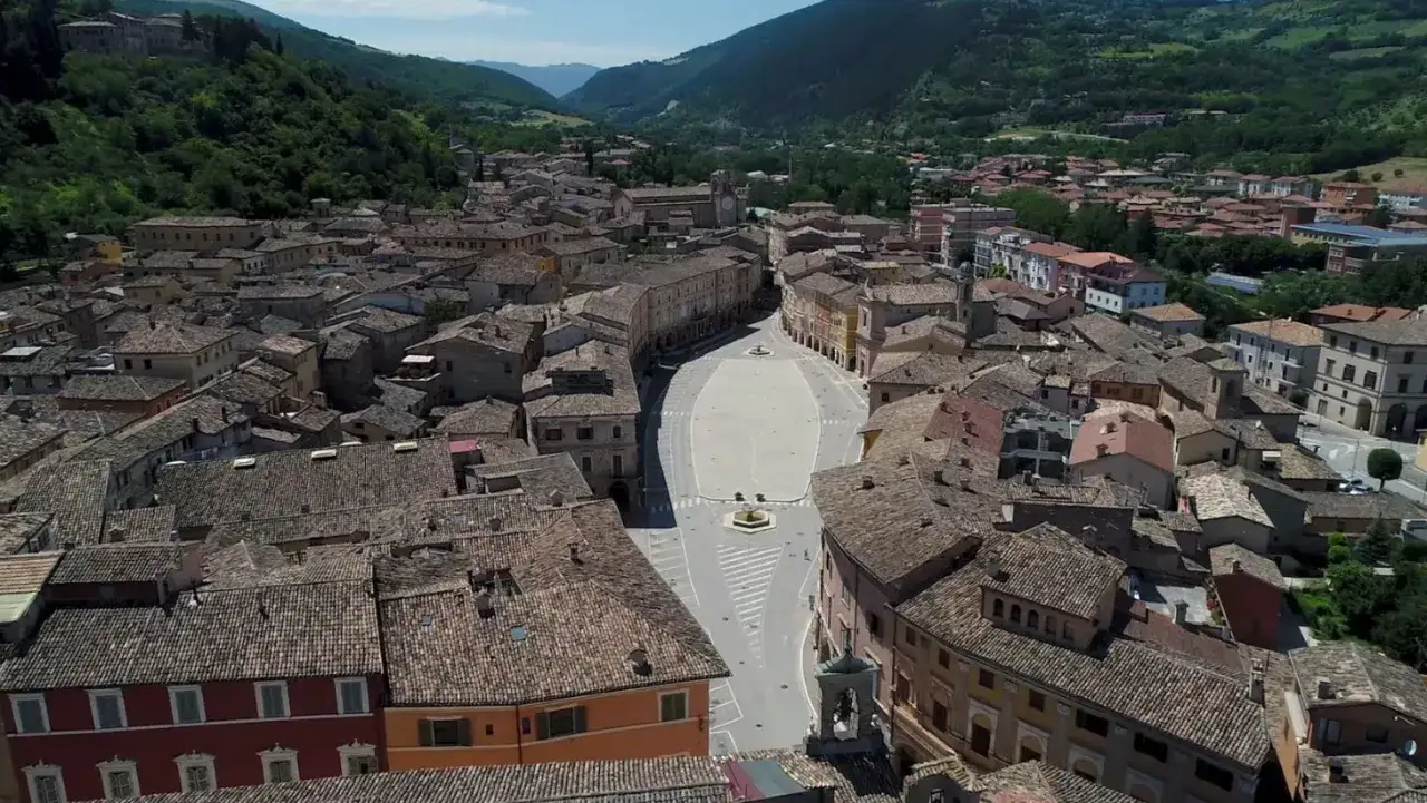 Vista aerea di San Severino Marche, con tetti in cotto e una piazza centrale.