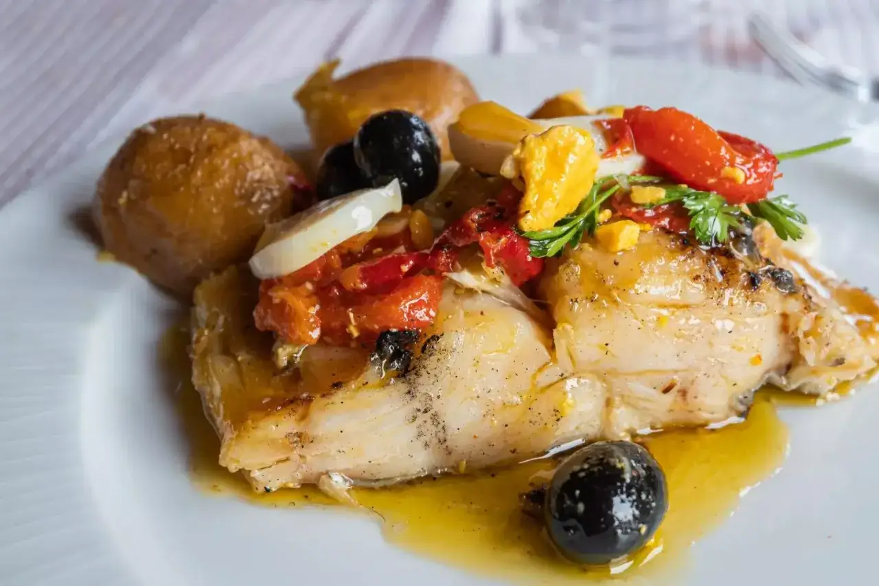 Stoccafisso all'Anconetana con patate, olive nere, pomodorini e uovo sodo. Un piatto gustoso e tradizionale.