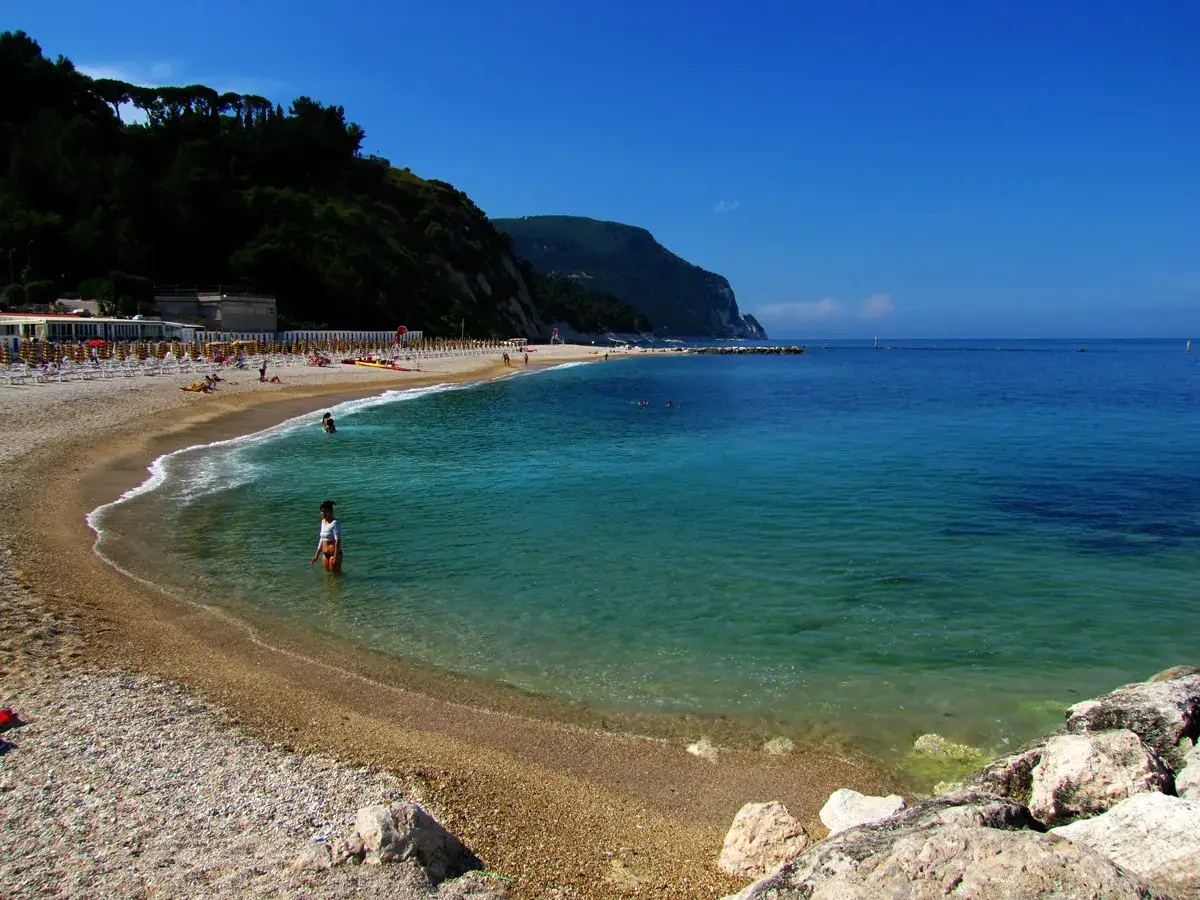 Spiaggia di Numana e Sirolo: acque cristalline, gente al sole e la costa del Conero. Un luogo incantevole da scoprire.