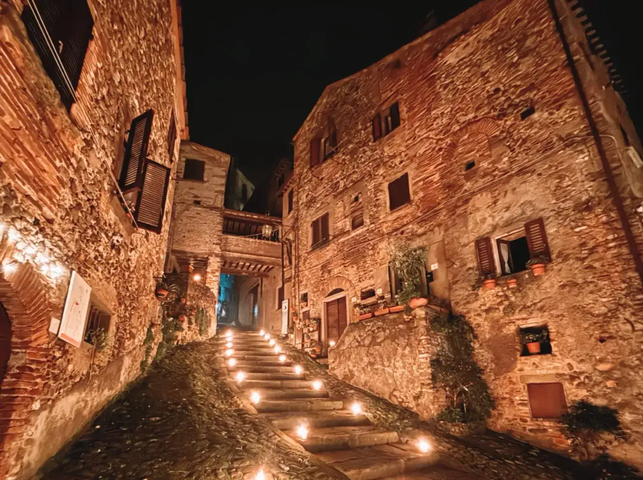 Una scalinata illuminata da candele in un vicolo di Pieve Santo Stefano, con antiche case in pietra e mattoni.