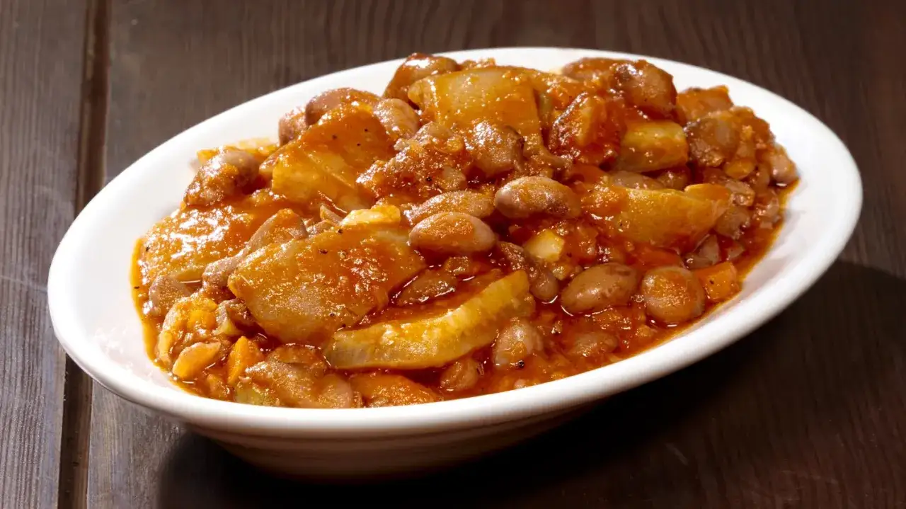Piatto di fagioli con le cotiche, un classico della ricetta marchigiana, servito in una ciotola bianca su un tavolo di legno scuro.