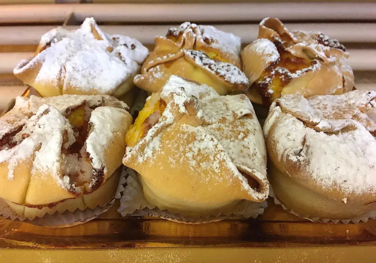 Calcioni di ricotta abruzzesi, dolcetti dorati con ripieno cremoso e una spolverata di zucchero a velo, pronti per essere gustati.