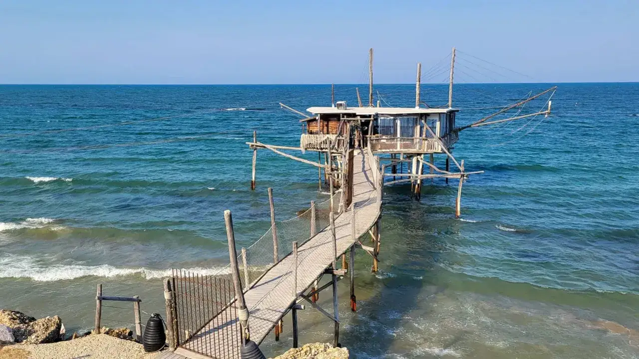Un trabucco tradizionale delle Marche si protende sul mare Adriatico, con una passerella in legno che conduce alla struttura di pesca.