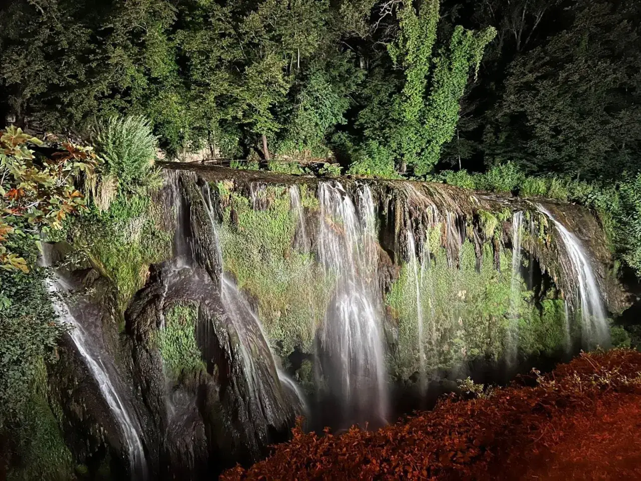 Cascata delle Marmore, un luogo magico da scoprire a Terni. Acqua che scende tra rocce e vegetazione rigogliosa, illuminata di notte.