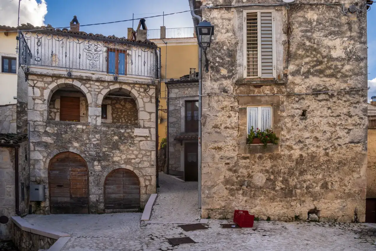 Antico vicolo di pietra, con archi e porte in legno. Un balcone in ferro battuto decora un edificio. Perfetto per scoprire cosa vedere a Pretoro.